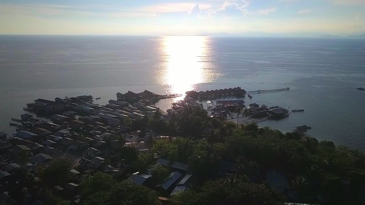 말레이시아의 황금빛 하늘을 배경으로 지역 마을과 바다를 향한 공중 비행, 슬로우 모션으로 앞으로 나아가는 긴 샷