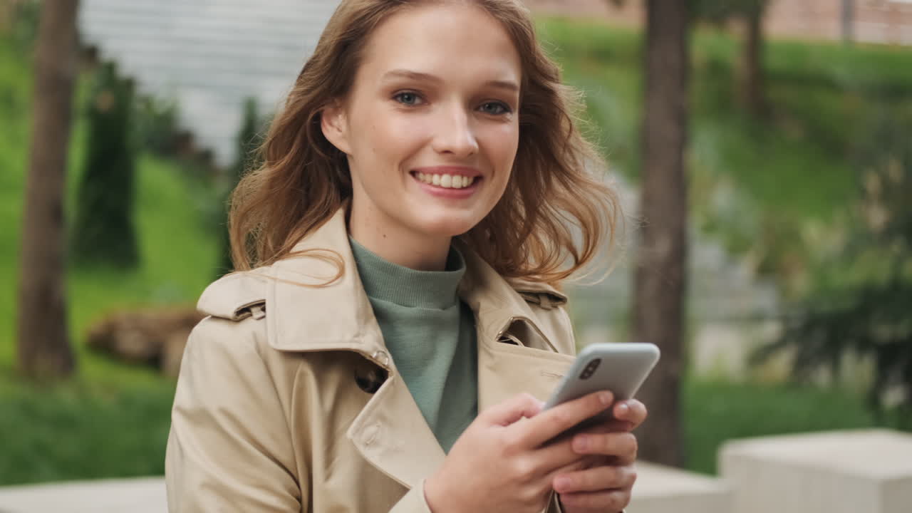 Caucasian female student using smartphone and looking at the camera.