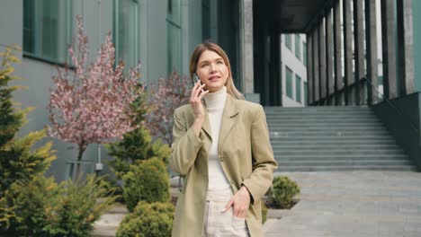 pretty young caucasian woman standing and talking on mobile phone in the street at sunset weather. people and technologies concept