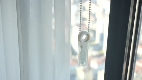 ventana con cortinas blancas y un control de cordón