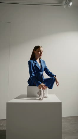 woman in blue pantsuit and white socks posing in a studio