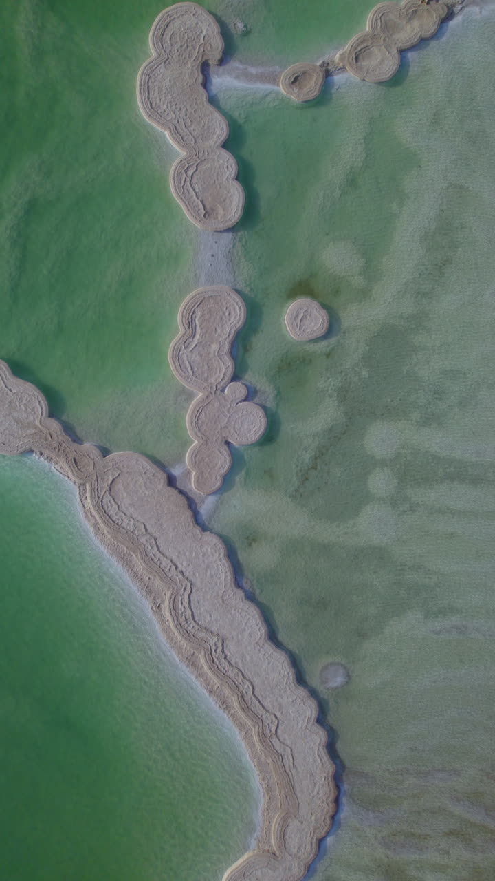 Vertical video top down view of huge lumps of salt created by the movement of water in the Dead Sea