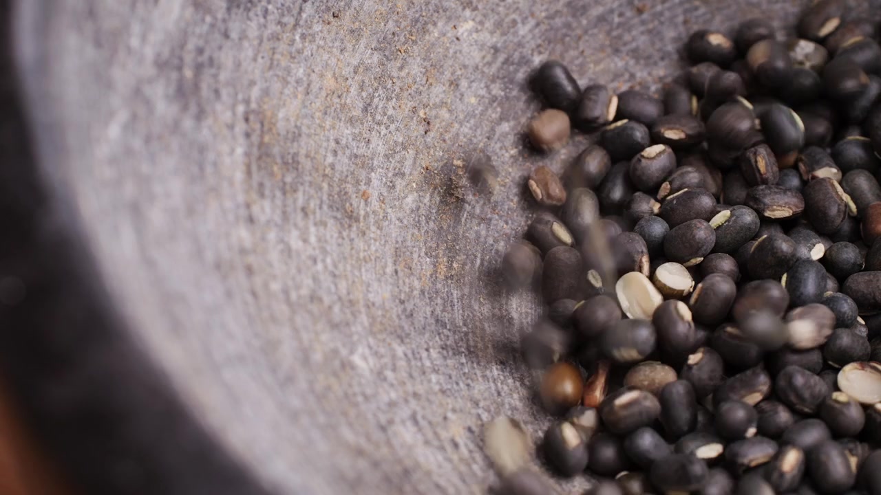 Black Gram Beans Pouring into a Rustic Stone Mortar