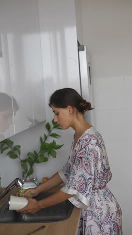 woman washing a cup in the kitchen