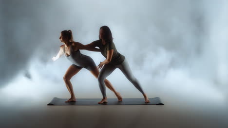 two women practicing partner yoga on a mat