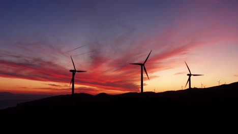 silhueta de turbinas eólicas, energia renovável, paisagem montanhosa, vista aérea durante o pôr do sol e céu colorido