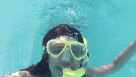 pretty brunette diving into swimming pool wearing snorkel