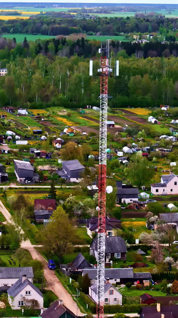 Radio tower rises above village rooftops and houses in peaceful rural sunset scene
