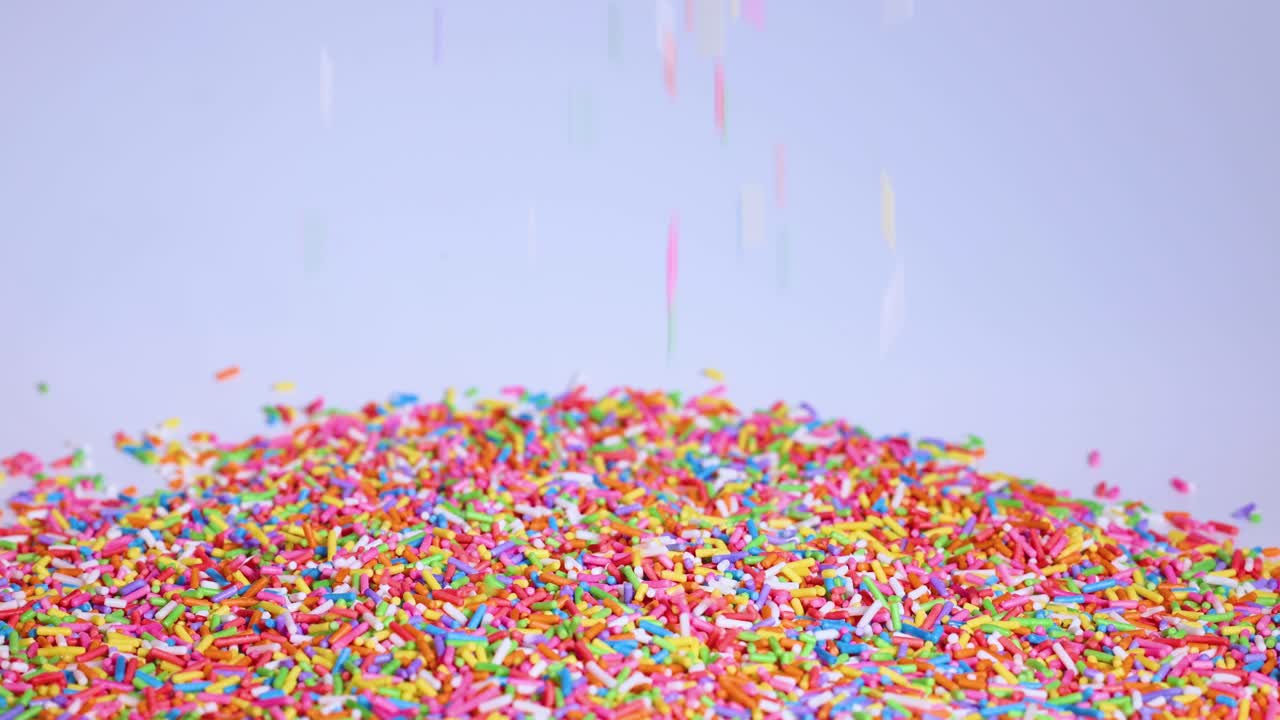 Vibrant sprinkles cascade onto a growing mound