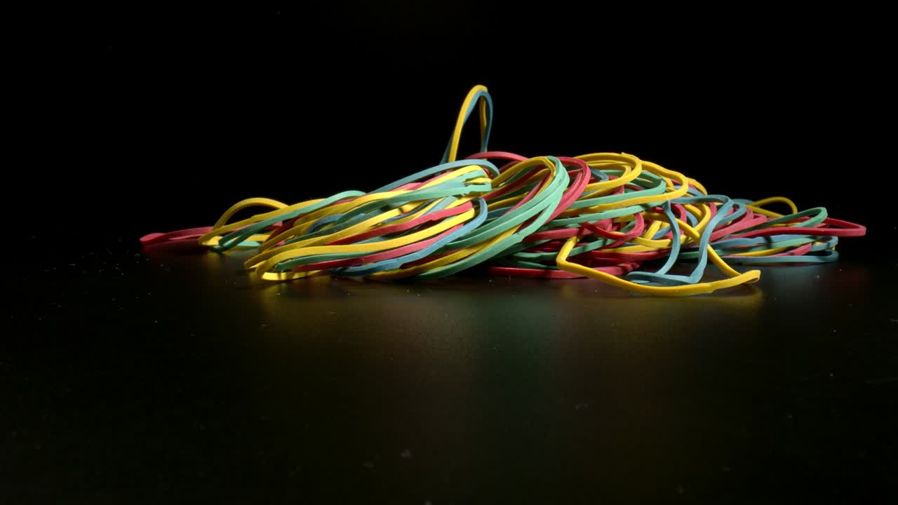 A bunch of rubber bands falling on black surface. Concept of Office Products. Stationery for home, office, school.