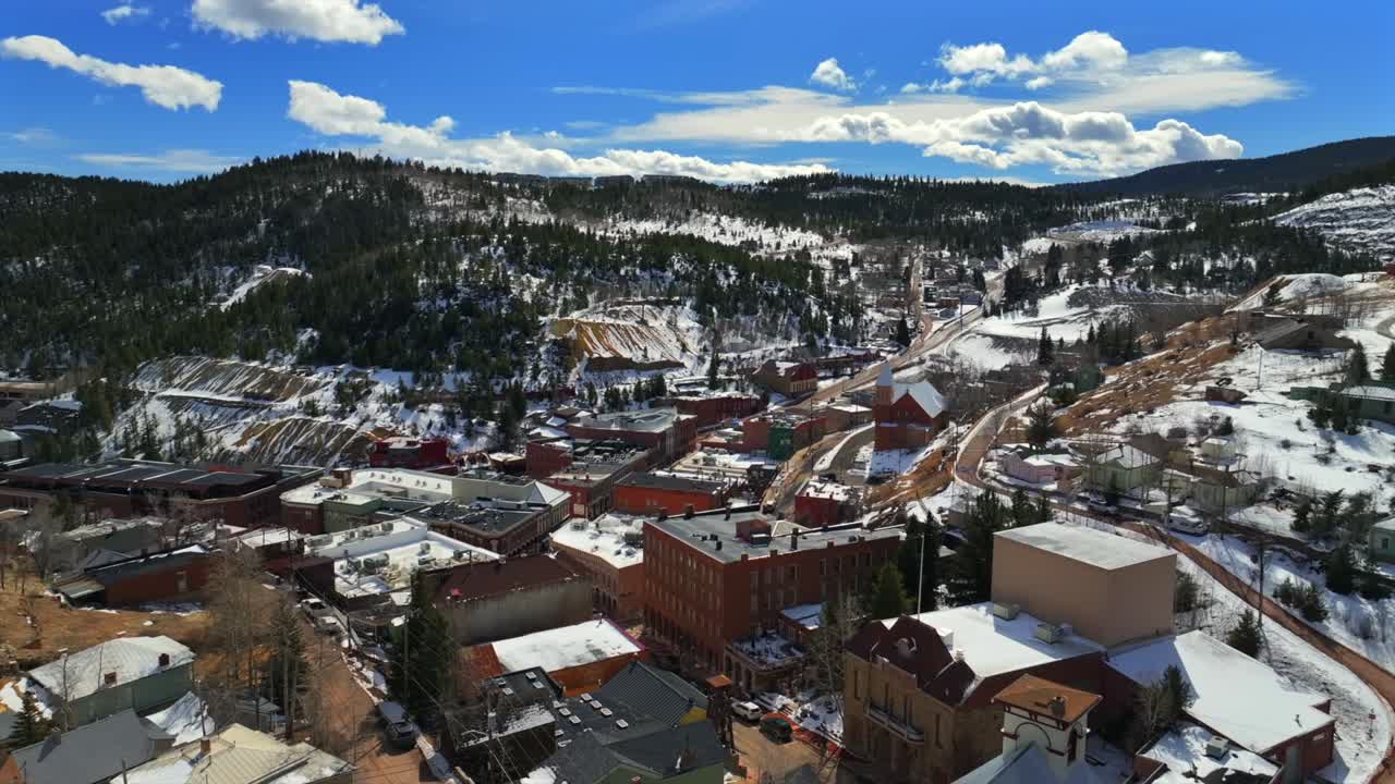 Historic downtown buildings Central City Black Hawk Colorado aerial drone view city townhall winter sunny daytime blue sky Gold mining town neighborhood streets casinos forward pan up motion