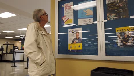 old woman at dmv office, reading real id info letter, waiting for service, in los angeles, california, usa