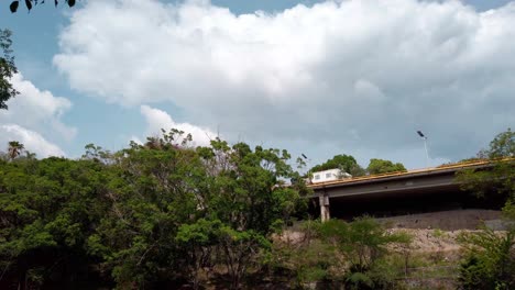 Fixed camera view of highway bridge above forested area in Morelos, Mexico