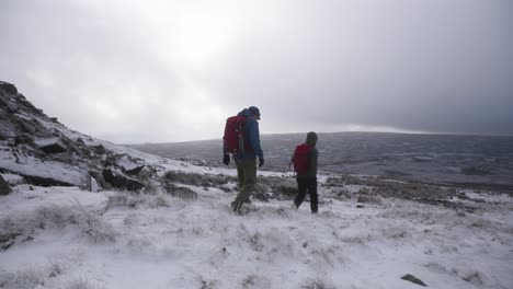 two men hiking through open tundra and moorland towards a distant horizon in a winter wonderland