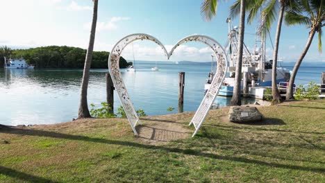 Creative-view-looking-through-a-love-heart-structure-over-the-calm-waters-of-a-coastal-fishing-village