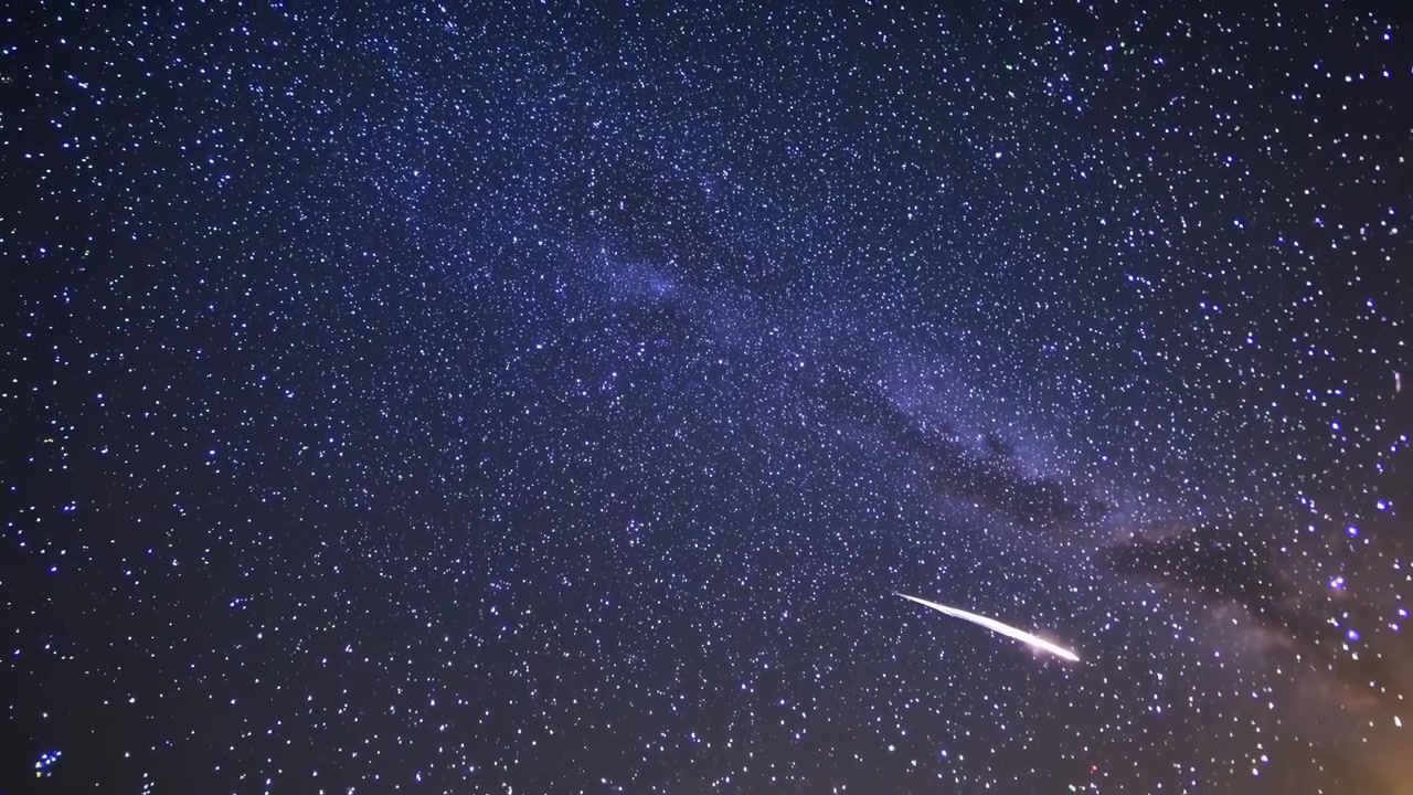 Meteora luminosa che attraversa un cielo notturno stellato con la Via Lattea