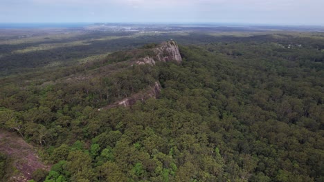 mount tinbeerwah lookout from above - steep rocky cliff surrounded by dense vegetation in queensland, australia. aerial shot