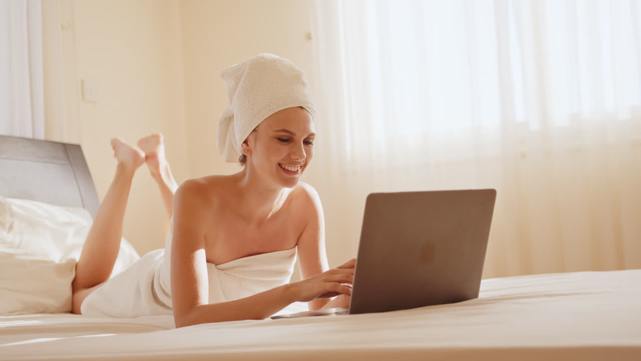 Donna che si rilassa a letto con il portatile.