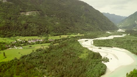 aerial view of soca river surrounded by a small town and many hills in slovenia.