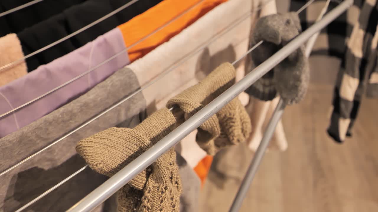 Woman hanging woolen socks to dry on indoor rack, close-up shot - 4K.