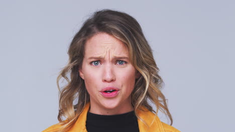 head and shoulders studio shot of angry woman shouting at camera in slow motion