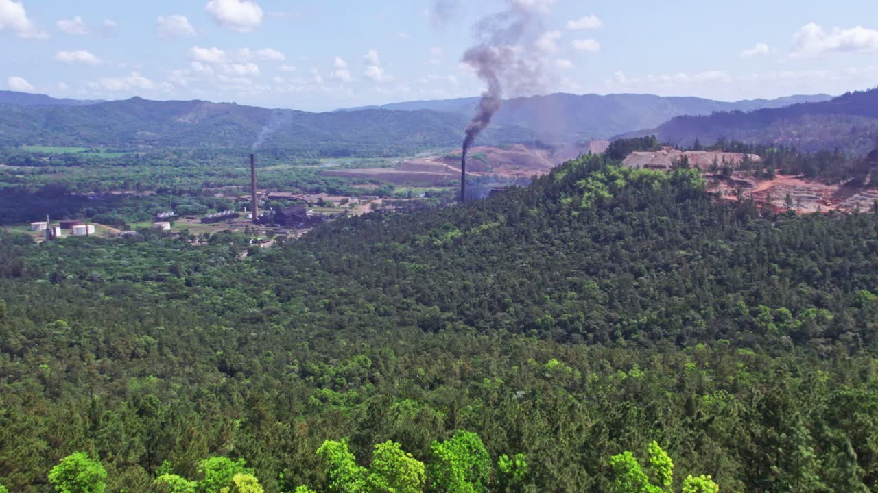 avance aéreo sobre un paisaje verde con chimeneas humeantes en la mina de níquel, loma miranda
