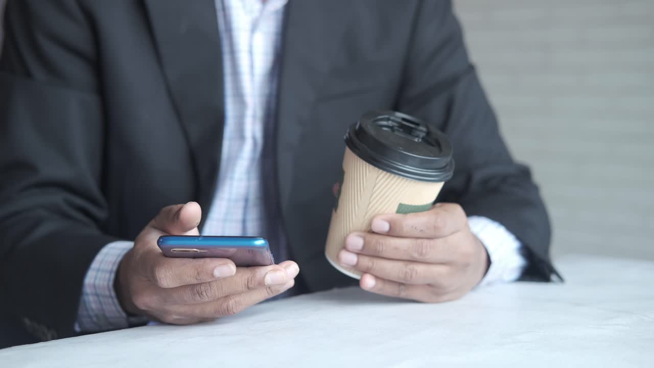 스마트폰을 사용하고 커피를 마시는 사업가