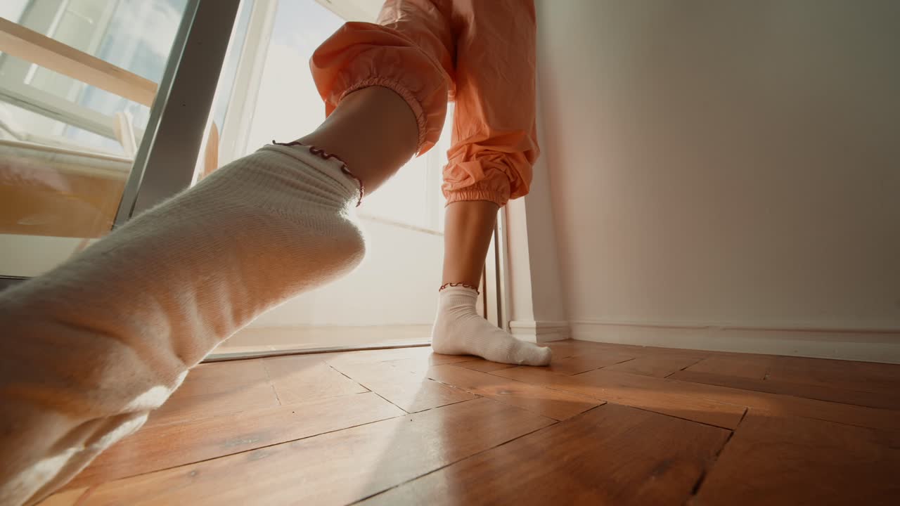 Person in socks and orange pants standing indoors