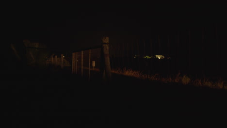 Coche-En-La-Carretera-Rural-Con-Valla-Junto-A-La-Vista-Nocturna.