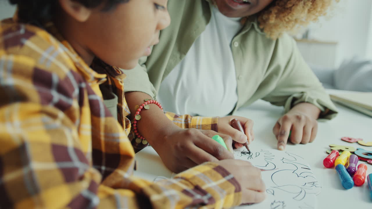 Preschool Boy Filling In Coloring Page with Help of Mom at Home