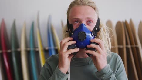 caucasian male surfboard maker wearing a breathing face mask