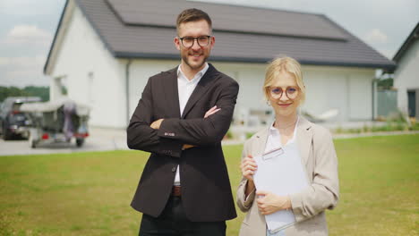 confident real estate agents in front of single-family house