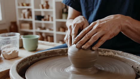 hands shaping clay on a potter's wheel in a pottery studio