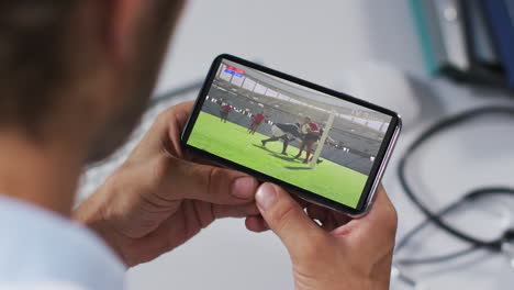 composición de un médico masculino viendo un partido de rugby en un teléfono inteligente