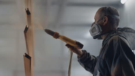 molar sprays paint on steel profiles in a respirator mask and protective suit in slow motion