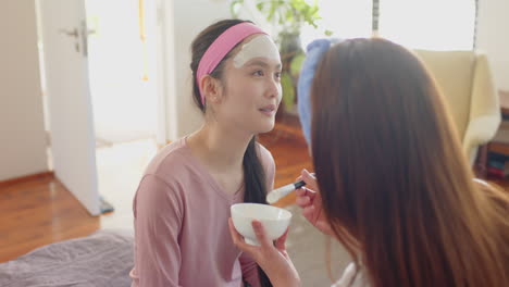 applying face mask, asian mother and daughter enjoying skincare routine together at home