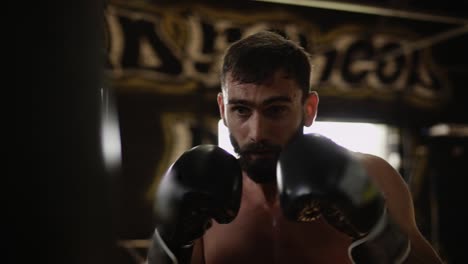 Boxer-training-on-punching-bag-in-gym.-Sportsman-working-with-punching-bag