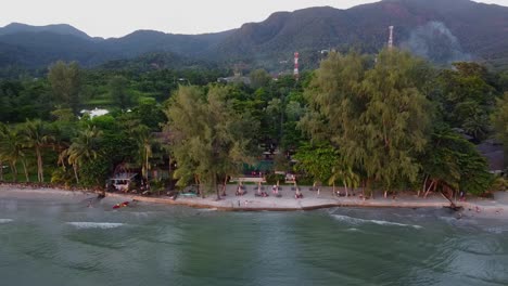 aerial: revealing shot of the jungle coast surrounded by mountains on the sunset, koh chang island in thailand, asia