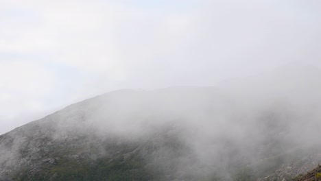 clouds moving along rocky mountain peak during foggy day after hike