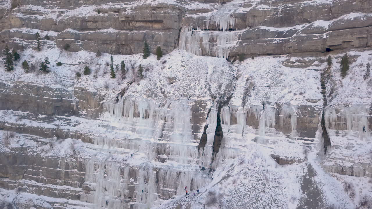 빙벽 등반가들은 록키산맥의 얼어붙은 폭포 옆에서 작업을 하고 있습니다 - 축소