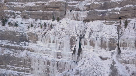 ice climbers work up the side of a frozen waterfall in the rocky mountains - zooming out