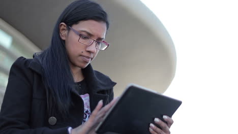 serious hindu woman typing on touch screen of tablet