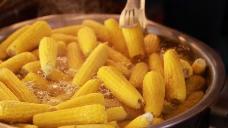 corn being boiled with tongs at market