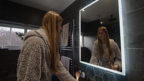 modelo femenino mirando en un espejo retroiluminado de baño maquillándose
