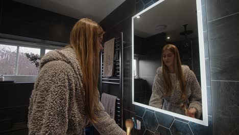 female model looking in a bathroom backlit mirror putting on makeup