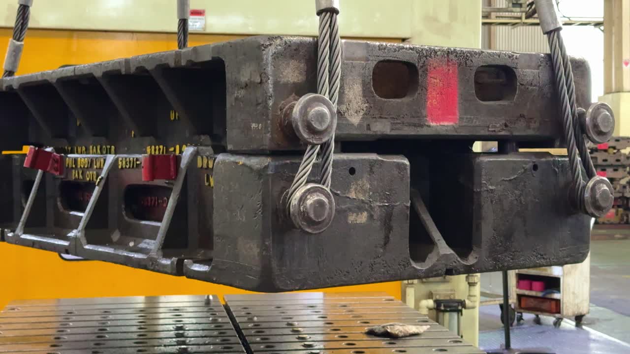 Massive steel mold component is hoisted by a crane in a factory environment. The video showcases heavy lifting, engineering processes, and modern industrial workflow
