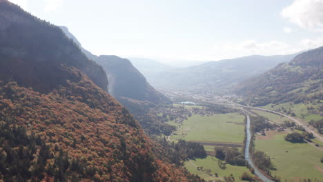 aerial of colorful forest on mountain ridge near green valley in autumn