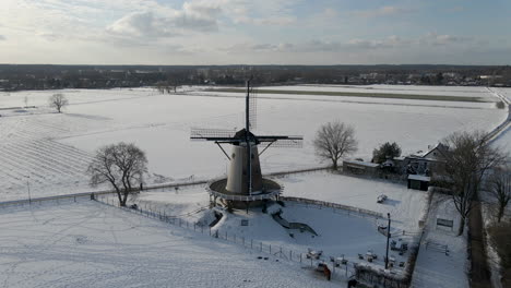 flying towards traditional windmill in rural snow covered landscape