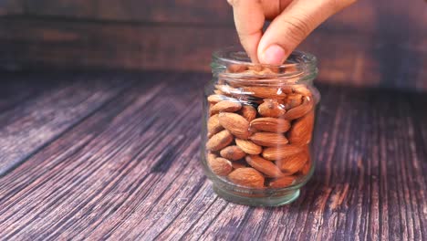 recogiendo almendras a mano de un frasco de vidrio