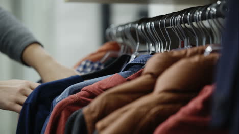 woman looks through jackets and shirts in the shopping mall